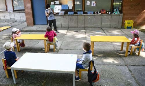 A teacher reads a book to kindergarten children in a school